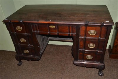 Lot 1380 - A stinkwood desk fitted with six small drawers around a shaped apron and raised on claw and...