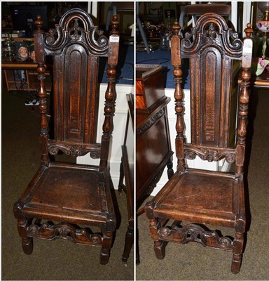 Lot 1393 - A pair of English joined oak high back chairs with carved top rails above boarded seats and...