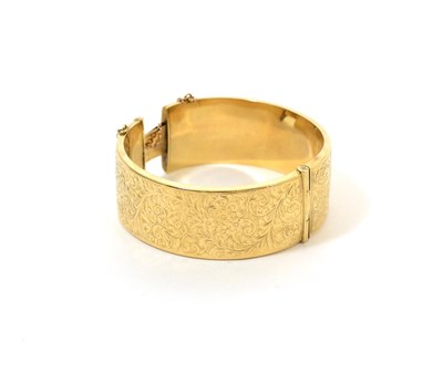 Lot 78 - A 9ct gold bangle, hinged and engraved, width 2.4cm