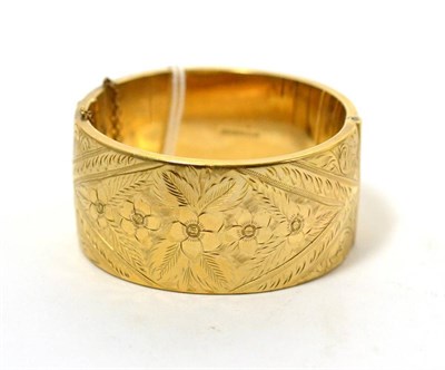 Lot 227 - A 9ct gold bangle, hinged and floral engraved, width 3.3cm