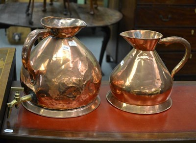 Lot 370 - A large copper jug with tap (converted) and a medium copper jug