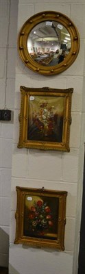 Lot 1111 - A reproduction gilt framed convex mirror, together with two still life of flowers oils in...