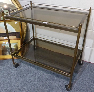 Lot 1132 - Gilt metal two tier trolley, with brass reeded supports, ball finials and smoked glass shelves