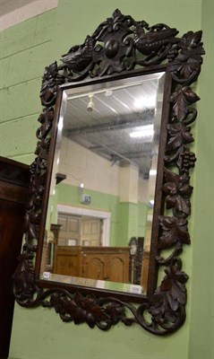 Lot 1206 - A Continental style oak wall mirror carved with vine and grapes and two birds to the surmount