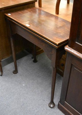 Lot 1305 - An 18th century oak foldover card table, with hinged lid above a shaped frieze and raised on...