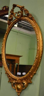 Lot 1323 - Decorative oval gilt wall mirror with carved swags