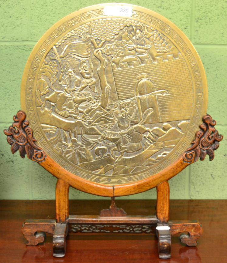 Lot 339 - A Chinese bronze mirror decorated with warriors on a hardwood stand