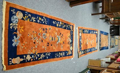 Lot 1090 - A pair of early 20th century Chinese rugs, each with an urn issuing flowers enclosed by indigo...