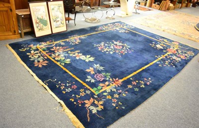 Lot 1092 - An early 20th century Chinese carpet, the indigo field centred by a roundel of naturalistic flowers