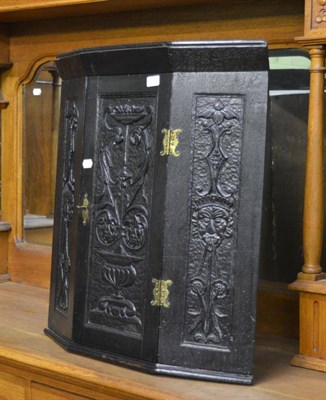 Lot 1302 - An ebonised carved corner wall cabinet