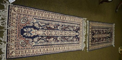 Lot 1365 - A pair of Kashmir prayer rugs, the indigo field centred by a column headed by an urn issuing...