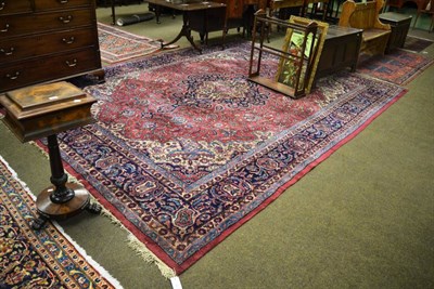 Lot 1376 - A Indian carpet, the raspberry field of scrolling vines around an indigo medallion framed and...