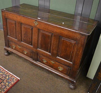 Lot 1414 - An 18th century joined oak mule chest, the plank top with hinged lid above four fielded panels,...