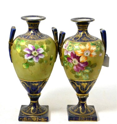 Lot 76 - A pair of twin handled porcelain vases decorated with flowers and highlighted in gilt