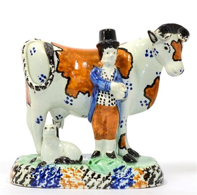 Lot 77 - A Yorkshire Prattware Cow Group, circa 1800, modelled as a cowherd wearing a top hat, standing next