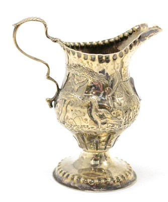 Lot 518 - A George III silver helmet form cream jug decorated in relief with a farm scene