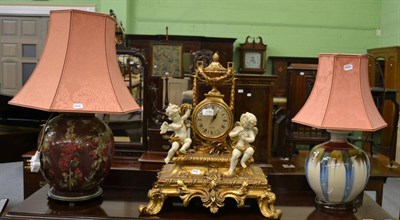 Lot 1149 - A modern gilt wood and faux marble mantel clock surmounted by cherubs and two table lamps