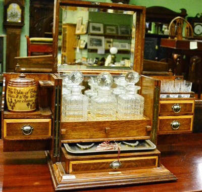 Lot 610 - An early 20th century blond oak tantalus/smokers cabinet, fitted with three decanters, six...