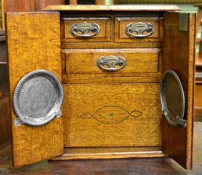 Lot 618 - A late Victorian blond oak smokers cabinet fitted with a revolving compartment fitted with an Adams