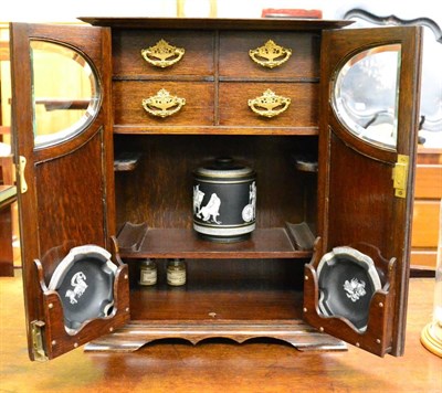 Lot 621 - An early 20th century oak smokers cabinet enclosed by two partially glazed panelled doors,...