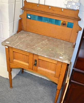 Lot 1131 - An early 20th century oak marble topped and tile backed washstand in the manner of Liberty, an...