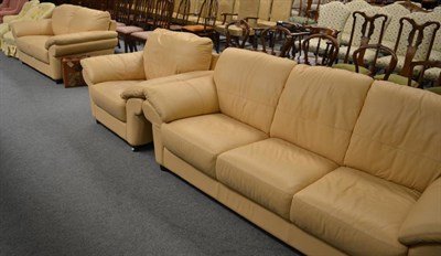 Lot 1299 - A cream leather three piece suite comprising three seater and two seater settees and an armchair