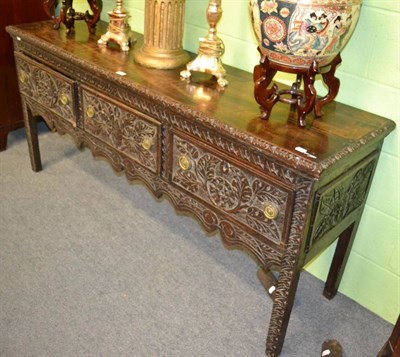 Lot 1371 - A carved oak dresser base fitted with three drawers