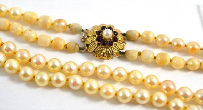 Lot 62 - A two row cultured pearl necklace with a garnet clasp, stamped '9CT' (a.f.)