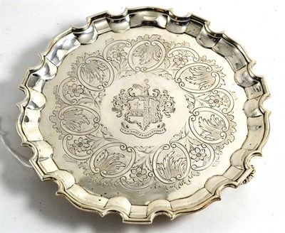 Lot 133 - A George III silver waiter, chased with a family crest, scrolls and flowers and raised on three...