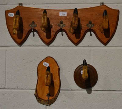 Lot 1002 - Deer slot coat rack; four deer slots (hoofs) mounted as coat hangers on a shaped oak fitting...