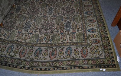 Lot 1119 - A machine made carpet of Oriental design, the ivory field with a one way design of trees and plants