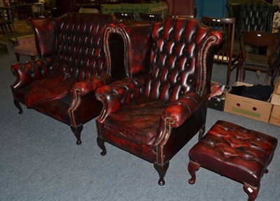 Lot 1162 - A red leather wingback two seater settee, armchair and foot stool