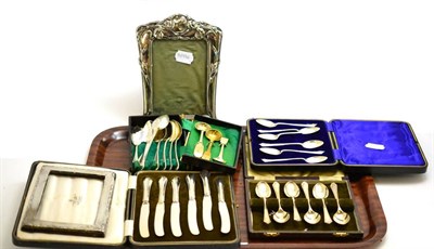Lot 128 - An Art Nouveau silver photograph frame, another frame, silver teaspoons and butter knives