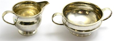 Lot 382 - An A E Jones Arts & Crafts silver cream and sugar with hammered decoration