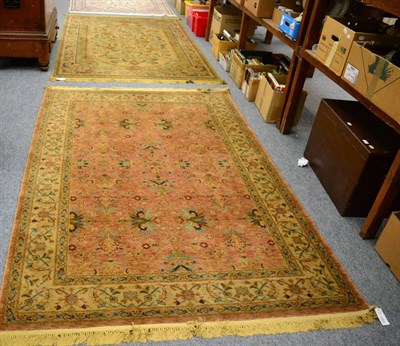 Lot 1093 - A machine made rug of Oriental design, the pale terracotta field of stylised plants enclosed by...