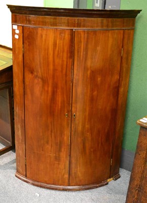 Lot 1221 - A 19th century mahogany bow fronted corner cupboard