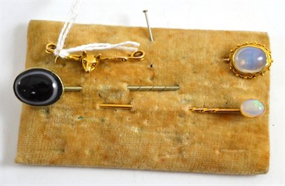 Lot 129 - A sardonyx stick pin, an opal stick pin, another oval stick pin and a fox mask and crop bar...