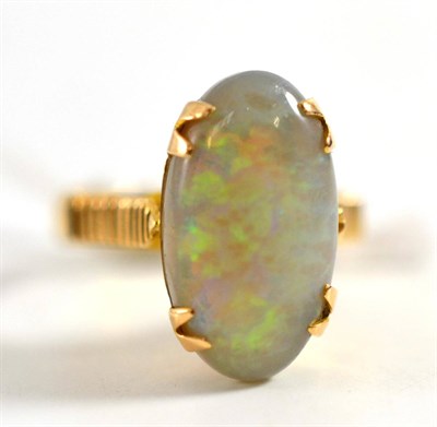 Lot 254 - An opal ring, the oval cabochon opal in a claw setting to linear decorated shoulders on a plain...