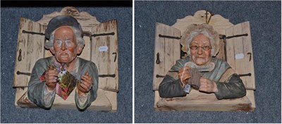 Lot 360 - Two plaster figural wall plaques of elderly figures leaning through a window