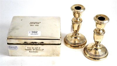 Lot 392 - Hinged silver cigarette box with inscription and a pair of loaded silver table candlesticks