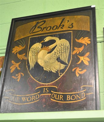 Lot 1164 - A heraldic painted wooden sign, titled Brook's, painted with a crest, being a swan, gorged with...