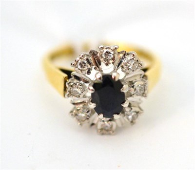 Lot 33 - An 18ct gold sapphire and diamond cluster ring, an oval cut sapphire within a spaced border of...