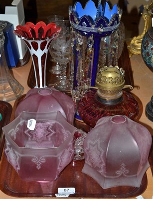 Lot 87 - Cranberry oil lamp and shades, lustres, etc