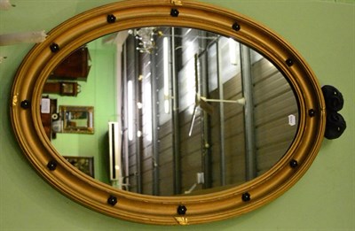 Lot 1176 - Gilt framed oval wall mirror with black ram's head mount