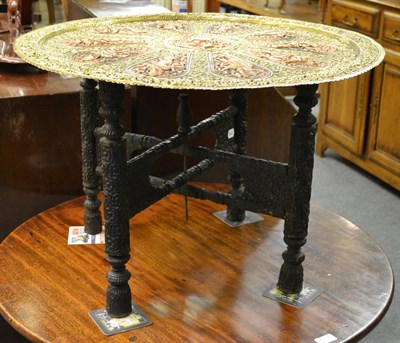 Lot 1217 - An Indian brass and copper table, the top intricately worked with panels of deities, with...