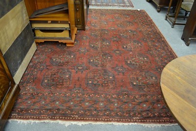 Lot 1228 - A Persian carpet, North Afghanistan, the madder field with three columns of elephant foot guls...