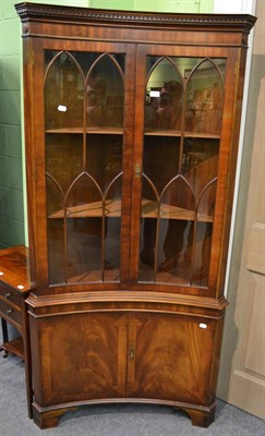 Lot 1293 - A reproduction mahogany concave glazed standing corner cabinet