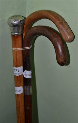 Lot 137 - A malacca walking cane with silver pommel and two walking sticks (3)