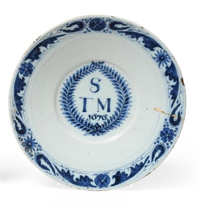 Lot 195 - An English Delft Marriage Plate, dated 1676, the central well painted in blue with S/TM 1676 within