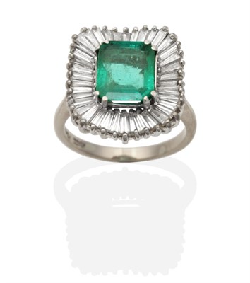 Lot 344 - An Emerald and Diamond Cluster Ring, an octagonal cut diamond in a claw setting within an...